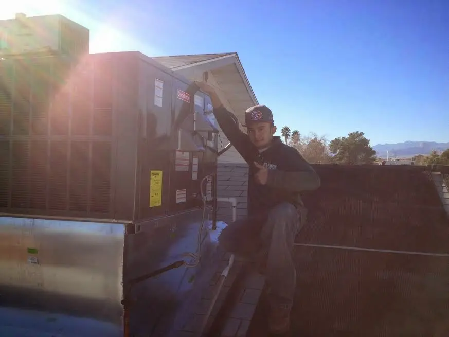 HVAC technician performing Air Duct Cleaning on a rooftop unit in Plymouth